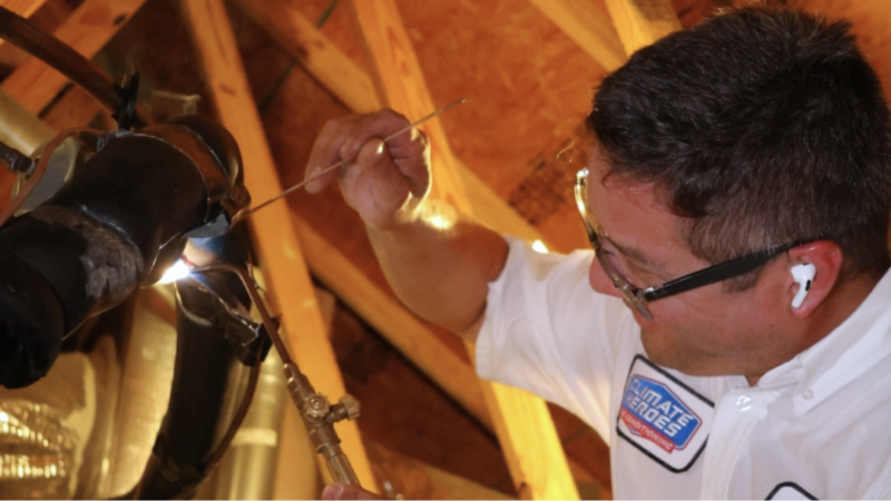 Climate Heroes service technician working on a furnace by brazing copper