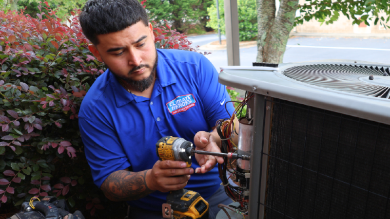 Climate Heroes service technician servicing an outdoor unit 