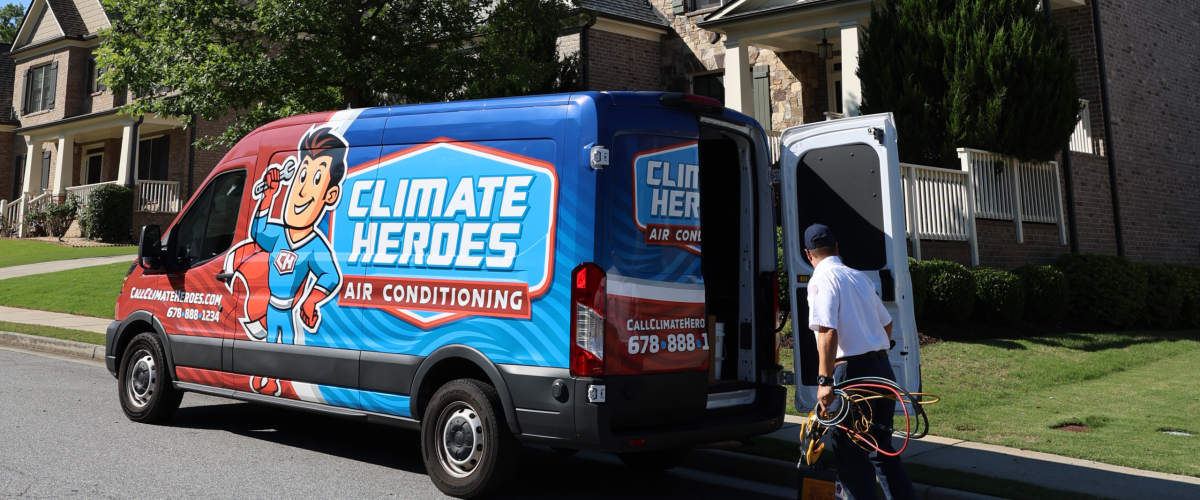 Climate Heroes HVAC technician carrying diagnostic gauges from a branded service van in a customer's driveway